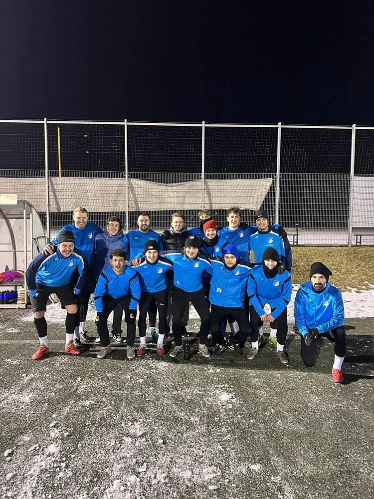 Mannschaft in blauen Jacken bei Frost und Flutlicht