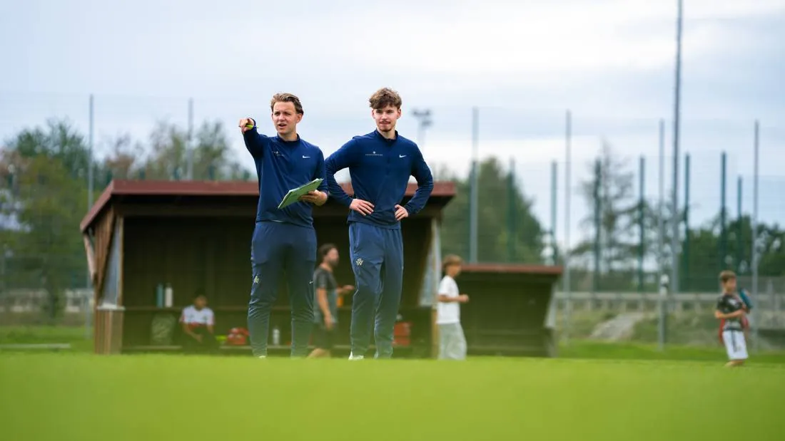 Zwei Spielerwerk-Coaches mit Klemmbrett auf dem Trainingsplatz